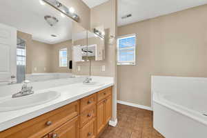 Master bath featuring baseboards, a bath, double vanity, and tile patterned floors