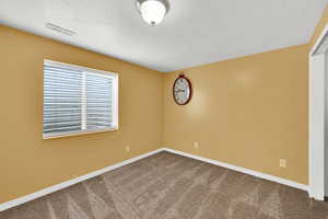 Basement bedroom featuring dark colored carpet, a textured ceiling, and baseboards