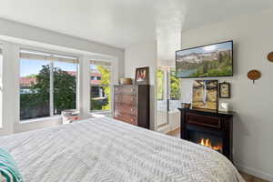 Bedroom with wood finished floors, a glass covered fireplace, and baseboards