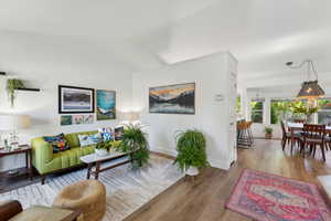 Living area with wood finished floors, baseboards, and vaulted ceiling