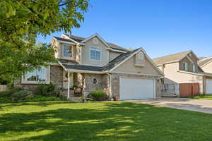Traditional-style house with stucco siding, driveway, stone siding, an attached garage, and covered porch