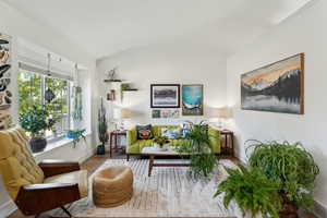 Living area with wood finished floors, lofted ceiling, and baseboards