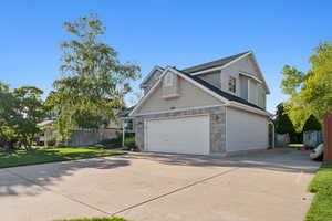 View of property exterior with concrete driveway, stone siding, and a garage