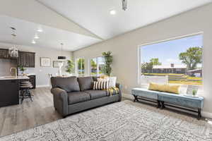 Living room with light wood-style flooring, baseboards, vaulted ceiling, and recessed lighting