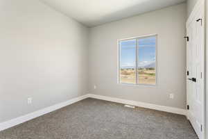 Unfurnished room with dark carpet and baseboards