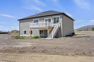 Rear view of house with stairway, a deck with mountain view, stucco siding, and central AC
