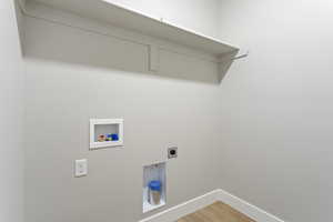 Washroom featuring hookup for a washing machine, hookup for an electric dryer, baseboards, and light wood-style flooring