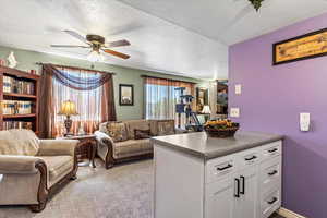 Living area featuring a textured ceiling, ceiling fan, and light colored carpet