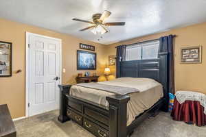 Carpeted bedroom featuring a ceiling fan, a textured ceiling, and baseboards