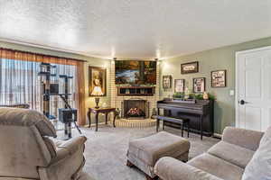 Carpeted living area featuring a fireplace, a textured ceiling, and baseboards
