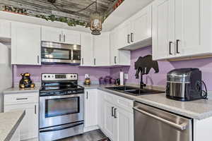 Kitchen featuring appliances with stainless steel finishes, a sink, and white cabinetry