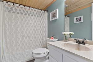 Full bath featuring wood ceiling, toilet, vanity, and shower / bath combo with shower curtain