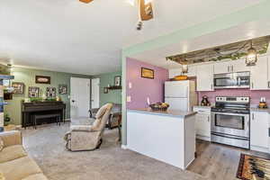 Kitchen with appliances with stainless steel finishes, open floor plan, white cabinets, a textured ceiling, and light countertops