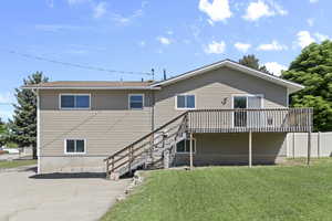 Rear view of property featuring a lawn, a deck, and stairs