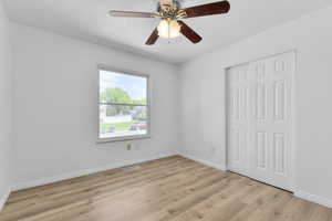 Unfurnished room featuring ceiling fan, light wood finished floors, and baseboards