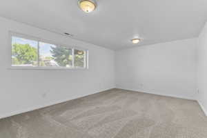 Empty room featuring light colored carpet and baseboards