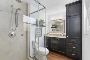 Full bathroom with a stall shower, wood finished floors, vanity, toilet, and a textured ceiling