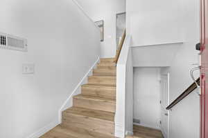 Stairway with wood finished floors and baseboards