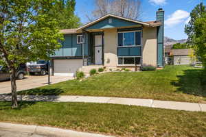 View of front of house with a chimney, concrete driveway, brick siding, an attached garage, and a mountain view