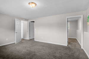 Unfurnished bedroom featuring carpet, a textured ceiling, and baseboards