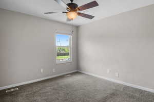 Unfurnished room featuring carpet flooring, baseboards, and ceiling fan