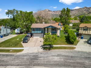 View of front of house with driveway, a mountain view, a garage, and a chimney