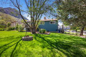 Back of property featuring a chimney, a lawn, and a fire pit