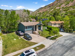 Ranch-style home with concrete driveway, a garage, a mountain view, a chimney, and a front yard