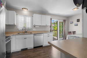 Kitchen featuring stainless steel appliances, a sink, dark wood finished floors, and white cabinetry