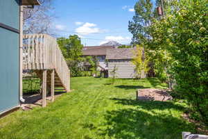 View of grassy yard featuring stairway and an outbuilding
