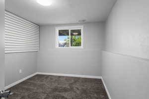 Empty room featuring carpet, a textured ceiling, and baseboards