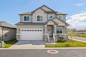 Craftsman-style home featuring a porch, driveway, a garage, stone siding, and stucco siding