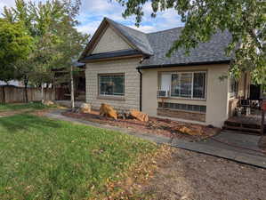 View of front of home with a shingled roof, a deck, and concrete block siding