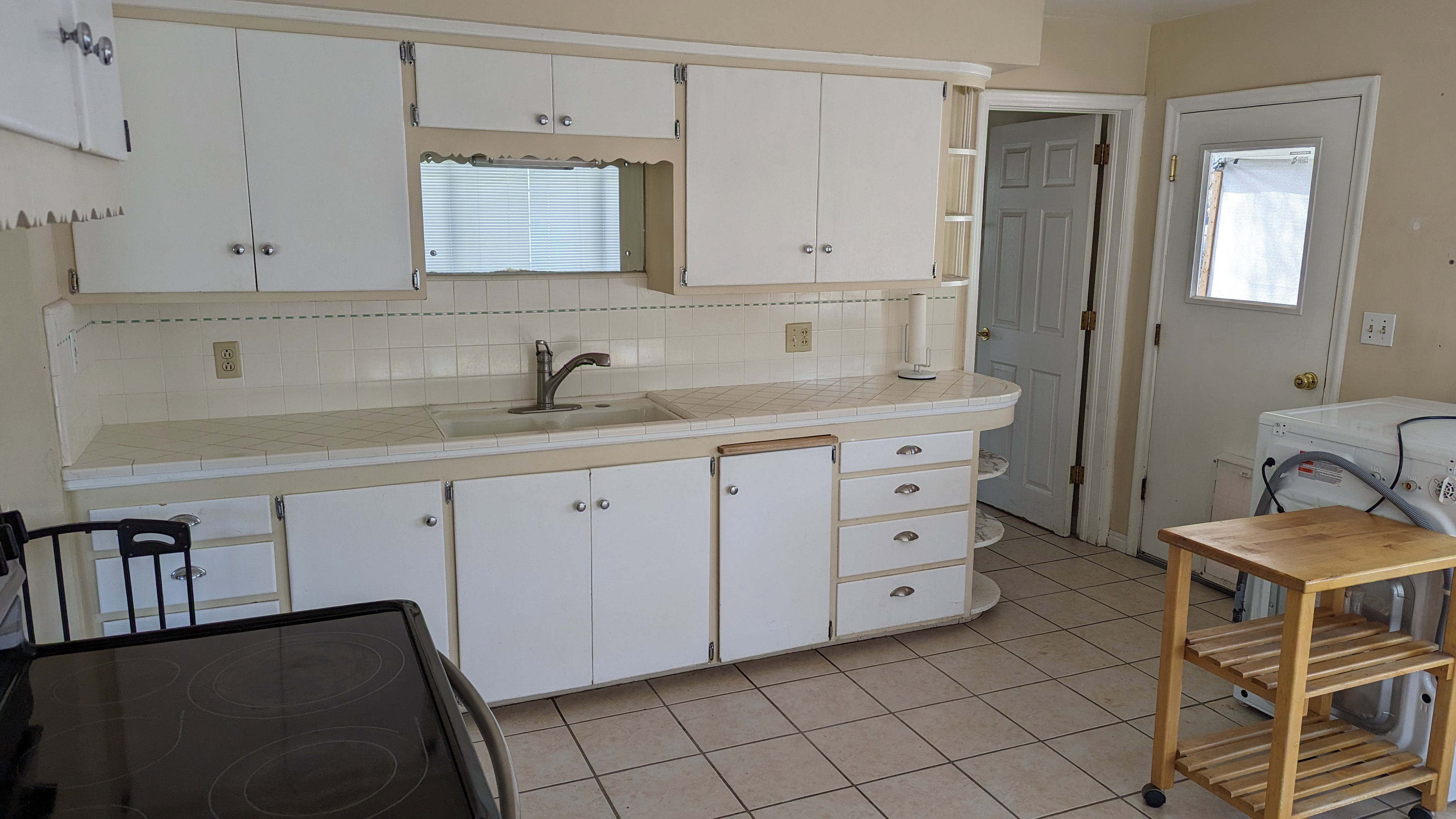 Kitchen featuring a sink, white cabinetry, light tile patterned floors, black range with electric cooktop, and backsplash