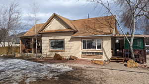 View of front of home featuring concrete block siding, fence, and a shingled roof