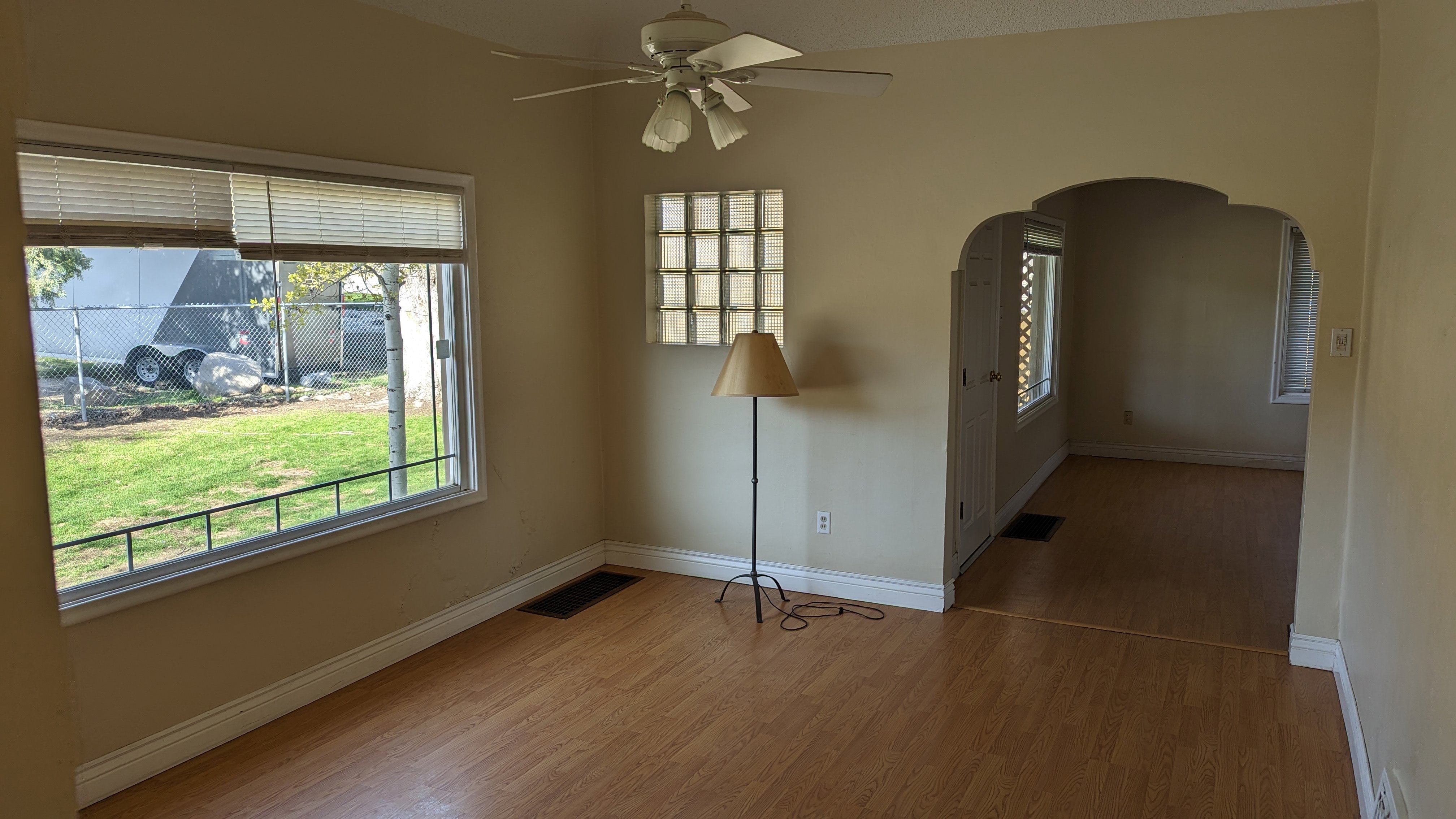 Empty room featuring baseboards, a ceiling fan, arched walkways, and wood finished floors