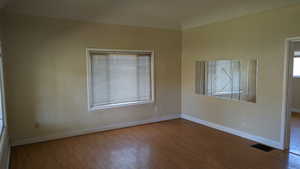 Unfurnished room with baseboards, wood finished floors, and visible vents