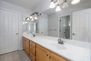 Bathroom with a chandelier, double vanity, and toilet