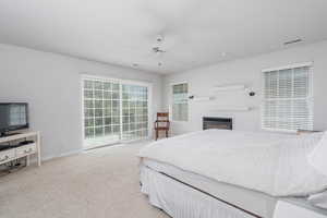 Bedroom featuring baseboards, carpet, a ceiling fan, and a glass covered fireplace