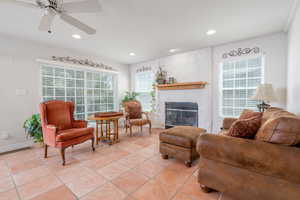 Living area featuring a glass covered fireplace, recessed lighting, light tile patterned floors, a ceiling fan, and baseboards