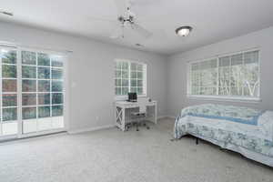 Carpeted bedroom with multiple windows, a desk, access to outside, and baseboards