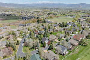 Aerial view of property and surrounding area featuring nearby suburban area and a mountain backdrop