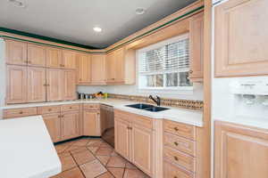 Kitchen featuring dishwasher, light brown cabinets, a sink, light tile patterned floors, and recessed lighting