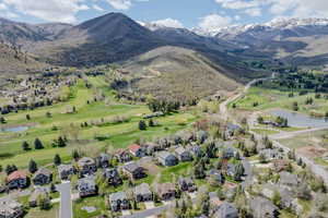 Aerial overview of property's location with a water and mountain view, a local golf course, and nearby suburban area