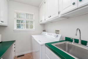 Clothes washing area featuring cabinet space, washing machine and clothes dryer, baseboards, and light tile patterned floors