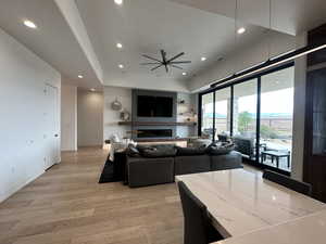 Living room featuring light wood-type flooring, recessed lighting, a ceiling fan, baseboards, and a glass covered fireplace
