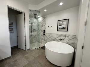 Bathroom featuring recessed lighting, a marble finish shower, a freestanding bath, tile walls, and baseboards