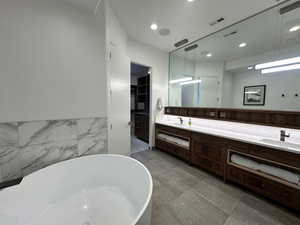 Full bathroom with a freestanding tub, double vanity, and recessed lighting