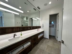 Full bath featuring a shower stall, baseboards, double vanity, and recessed lighting