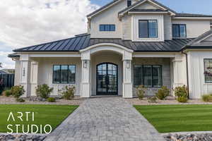Property entrance with a standing seam roof, a yard, and board and batten siding